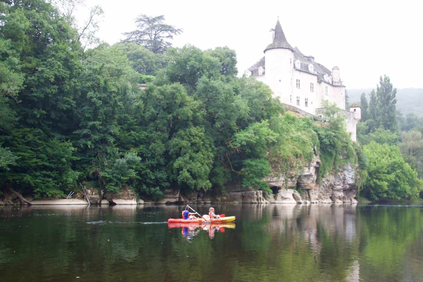 Image of Châteaux de la Treyne with people canoeing in front of it.